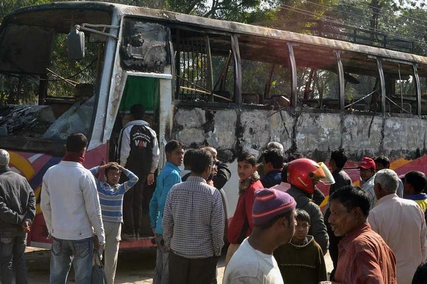 Onlookers surround the wreckage of a burnt bus allegedly set on fire by Bangladesh Nationalist Party (BNP) supporters during a blockade in Rangpur on Jan 14, 2015. Bangladesh security forces have arrested more than 7,000 opposition activists since th