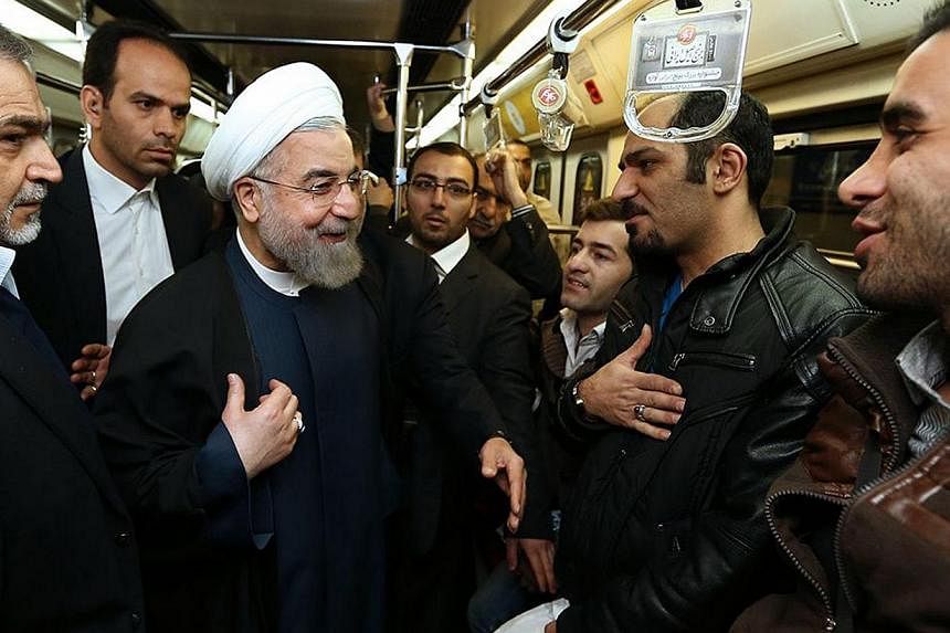 A handout picture released by the official website of the Iranian President Hassan Rouhani shows him (third from left) speaking with Iranian commuters in the subway on the way to his office in Tehran on Jan 19, 2015, in a move to encourage people to 