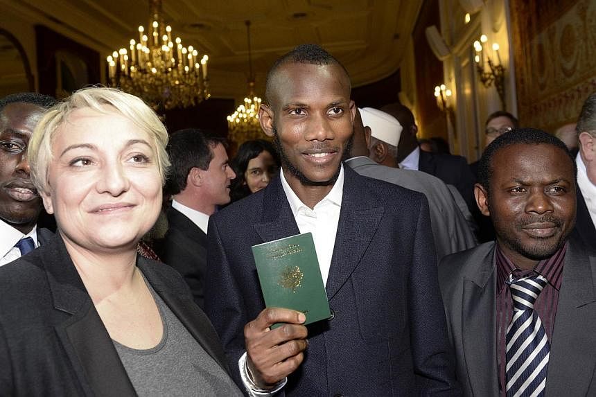 Mr Lassana Bathily, a man of Malian origin described as a "hero" after he helped hostages at a Jewish supermarket hide during last week's Paris attacks, holding his French passport following a ceremony on Jan 20, 2015&nbsp;at which was awarded French