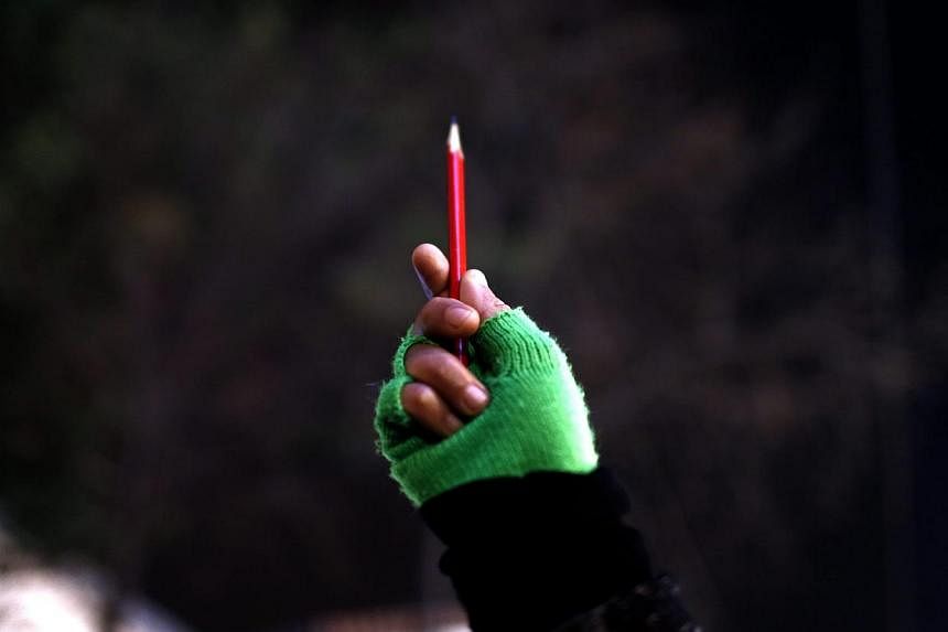 A woman holds a pencil outside the French Consulate in Istanbul, Turkey, Jan 8 2015, during a gathering to pay tribute to the victims of the Jan 7 attack on the Paris headquarters of French satirical magazine Charlie Hebdo. -- PHOTO: EPA