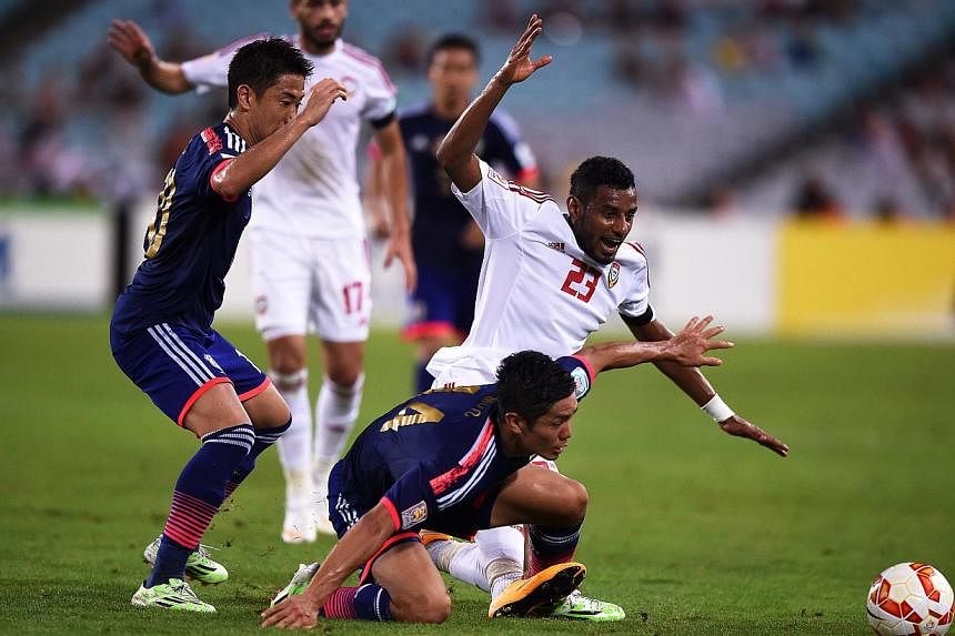 Japan's Yoshinori Muto (bottom) in action against Mohamed Ahmed (right) of the UAE during the AFC Asian Cup 2015 quarter final soccer match between Japan and the United Arab Emirates at Stadium Australia in Sydney, Australia on Jan 23, 2015. -- PHOTO