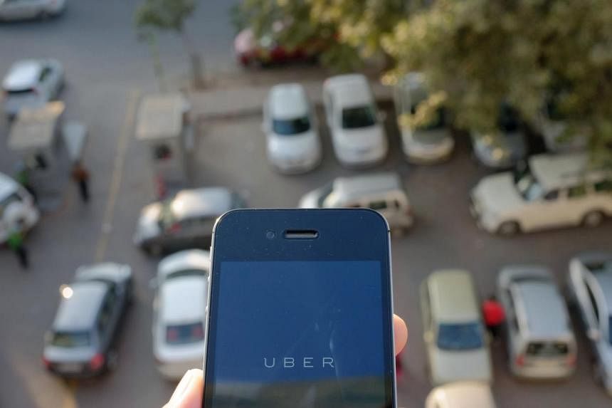 In this photograph taken on Dec 7, 2014 the Uber smartphone app, used to book taxis using its service, is pictured over a parking lot in the Indian capital New Delhi. United States taxi-hailing app maker Uber Technologies has restarted services in In