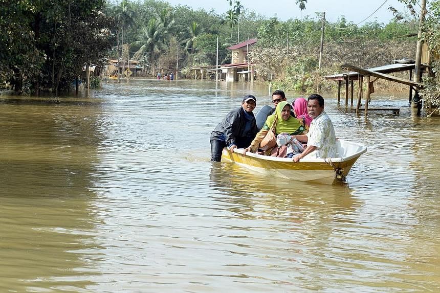 Villagers on their way by boat to get food at a relief centre in Kelantan, Malaysia. A Muslim foundation has raised almost $290,000 in less than a week in aid of the recent catastrophic floods in eastern Malaysia. -- ST PHOTO: AZIZ HUSSIN