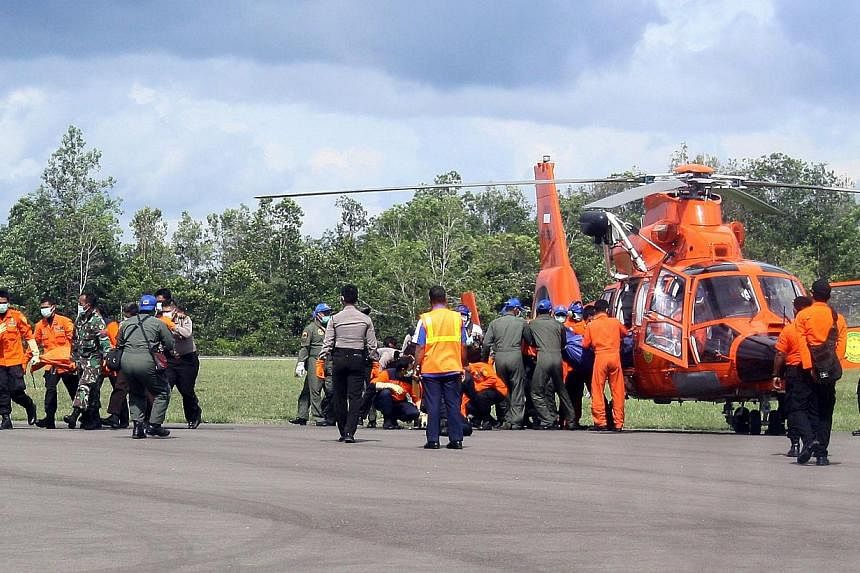 Indonesian rescue personnel unloading bags containing bodies which were recovered from the underwater wreckage of AirAsia flight QZ8501, from a search and rescue helicopter in Pangkalan Bun on Jan 24, 2015. -- PHOTO: AFP