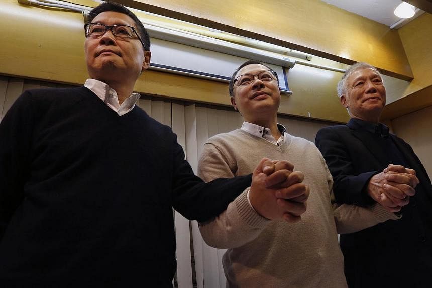 Hong Kong's original Occupy organisers Benny Tai (centre), Chan Kin Man (left) and Chu Yiu Ming joining hands during a news conference on their voluntary surrender to the police, on Dec 2, 2014. -- PHOTO: REUTERS