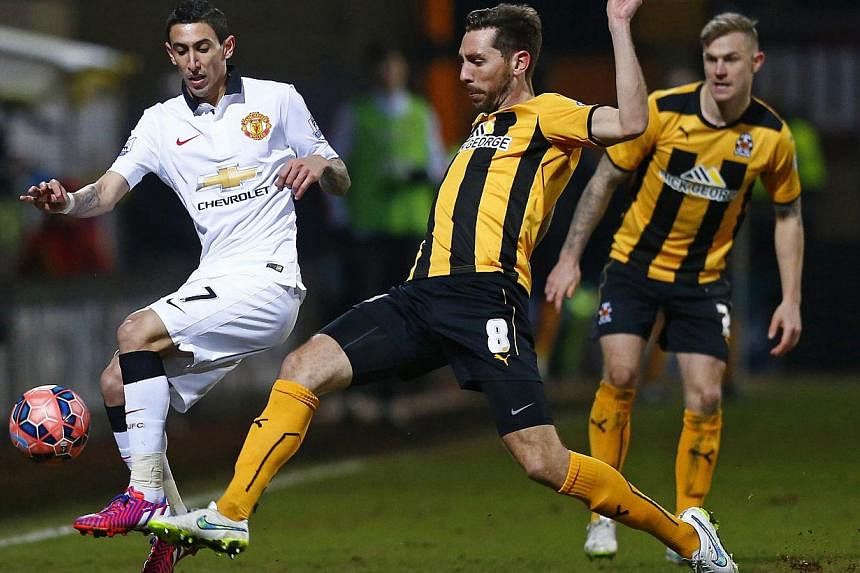 Manchester United's Angel Di Maria (left) is challenged by Cambridge United's Tom Champion during their FA Cup match at The Abbey Stadium in Cambridge on Jan 23, 2015. The match ended in a 0-0 draw. -- PHOTO: REUTERS