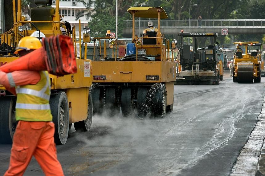 Road resurfacing works being conducted along Paterson Road, adjacent to Orchard Boulevard, where an oil spill took place in the early hours of Jan 15, 2015. -- PHOTO: ST FILE