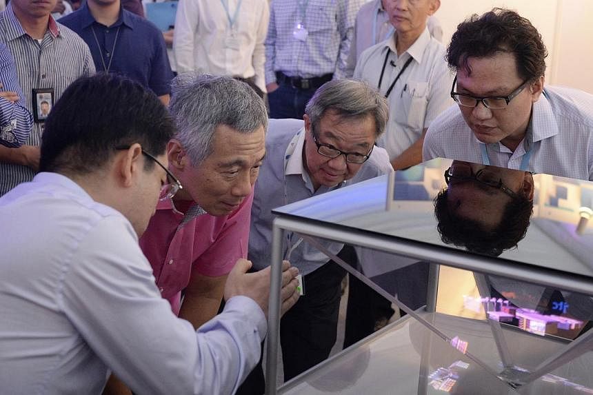 PM Lee takes a close look at a 3D holographic display system prototype with (from left) Spectral Reality director Bernard Song, JTC Corporation chairman Loo Choon Yong and Rock Nano Global CEO Ang Chong Lai.