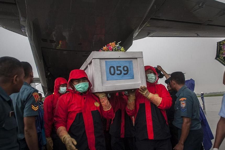 Indonesian rescue personnel unloading a coffin bearing a body recovered from the underwater wreckage of AirAsia flight QZ8501 from a military plane on arrival at Surabaya on Jan 23, 2015. Salvage teams on Jan 24 launched an operation to raise the pla
