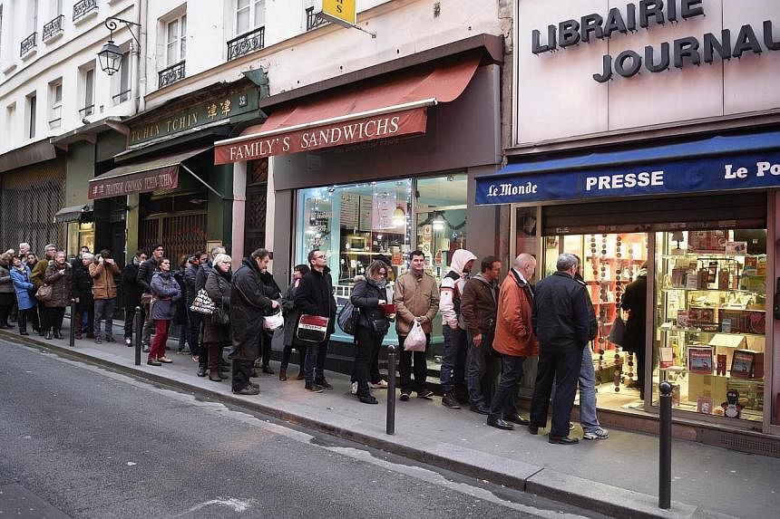 People waiting outside a newsagents in Paris on Jan 14, 2015 as the latest edition of French satirical magazine Charlie Hebdo goes on sale. -- PHOTO: AFP
