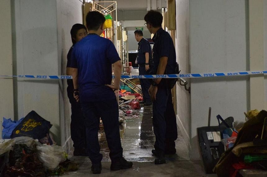 Police officers standing outside the flat of a man who set his own apartment on fire after attacking two of his neighbours with a parang. -- ST PHOTO: ALPHONSUS CHERN
