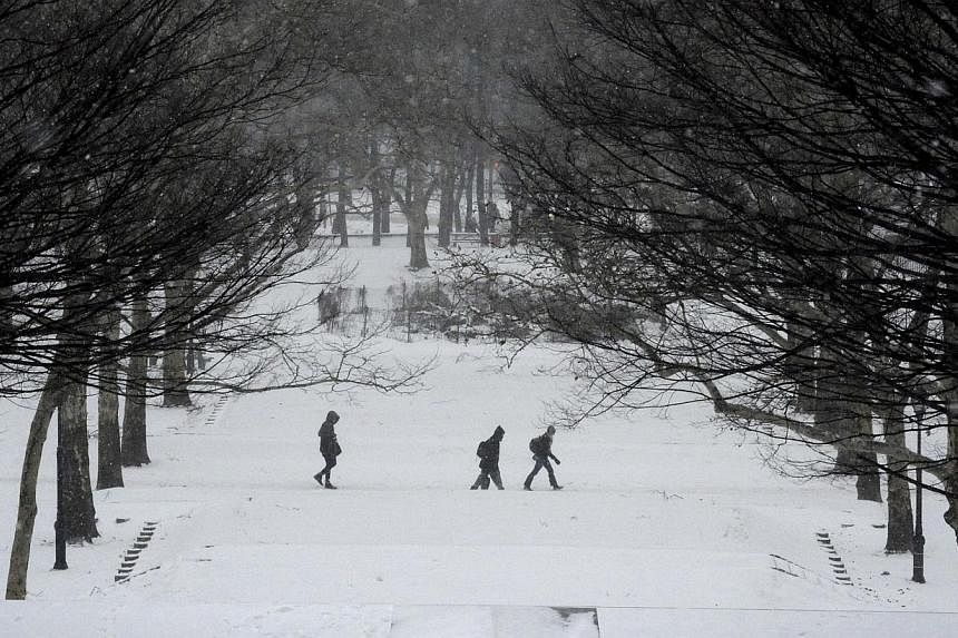 People walk in falling snow in Fort Greene Park in the Brooklyn borough Brooklyn in New York City on Jan 26, 2015. -- PHOTO: REUTERS