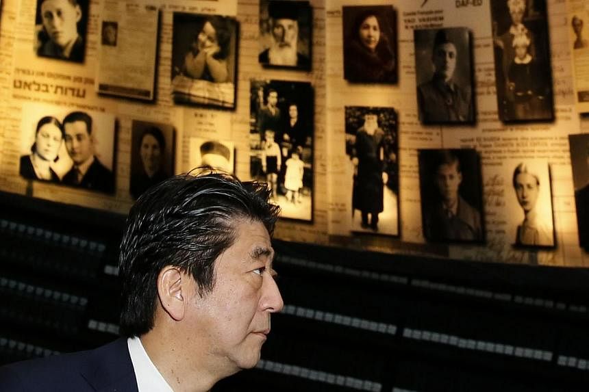 Japanese Prime Minister Shinzo Abe looks at pictures of Jewish Holocaust victims at the Hall of Names on Jan 19, 2015 during their visit to the Yad Vashem Holocaust Memorial museum in Jerusalem commemorating the six million Jews killed by the Nazis d