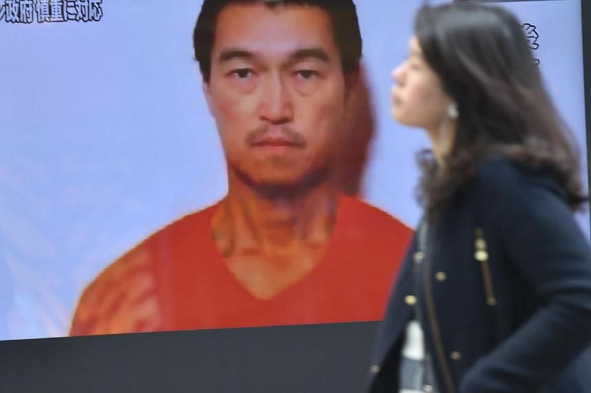 A pedestrian walks past a TV screen in Tokyo on Jan 26, 2015 showing news reports about Japanese journalist Kenji Goto being held by Islamic militants. Japan is working with Jordan to free both Goto and a Jordanian pilot, officials said on Tuesday, d