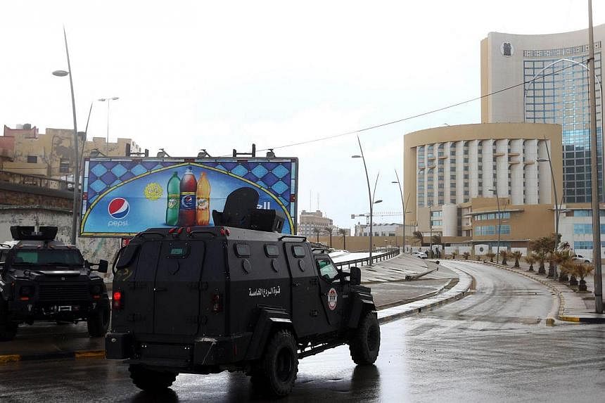 Libyan security forces and emergency services near the Corinthia Hotel (right) in Tripoli on Jan 27, 2015,&nbsp;after Islamic State in Iraq and Syria (ISIS) fighters said they staged an attack on it. -- PHOTO: AFP