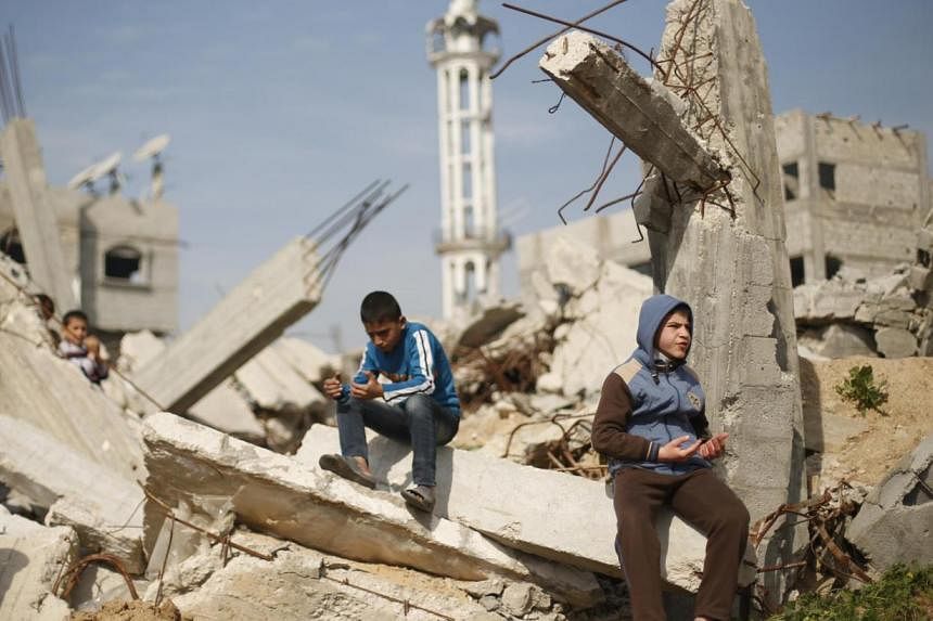 Palestinian boys attend Friday prayers as they sit at the remains of a house that witnesses said was destroyed by Israeli shelling during a 50-day war last summer, in the Shejaia neighbourhood east of Gaza City on Jan 23, 2015. -- PHOTO: REUTERS