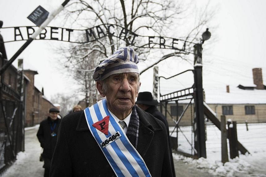 Survivors walk out the gate with the sign saying "Work makes you free" after paying tribute to fallen comrades at the "death wall" execution spot in the former Auschwitz concentration camp in Oswiecim, Poland, on the 70th anniversary of the liberatio