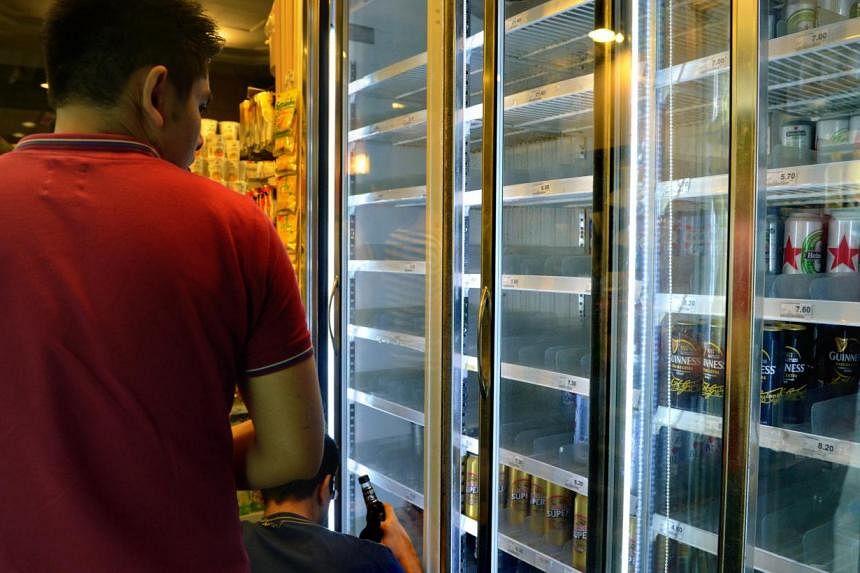 A customer looking at some alcoholic drinks at a 7-Eleven store in Clarke Quay. Four out of five people here support the Bill to outlaw late night drinking, a survey shows. -- ST PHOTO: KUA CHEE SIONG