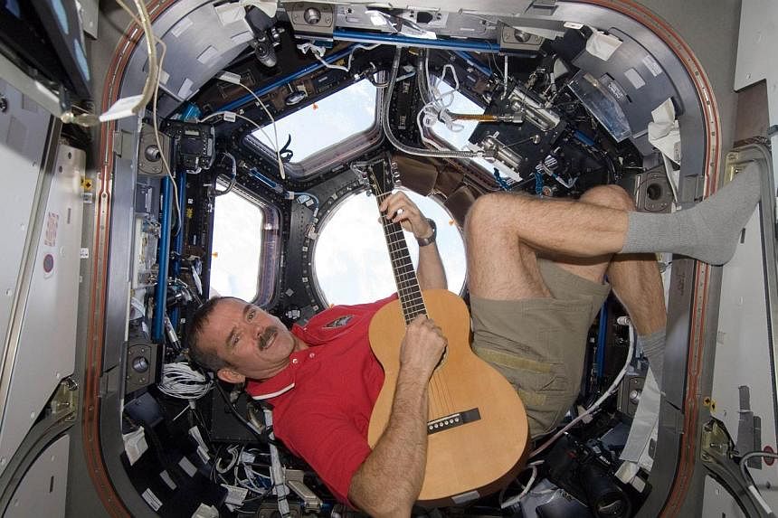 Canadian Space Agency astronaut Chris Hadfield called the discovery of a moon trailing asteroid 2004 BL86 "strangely delightful" on Twitter. Here in this NASA photo taken on Christmas 2012 he strums his guitar in the International Space Station. Hadf