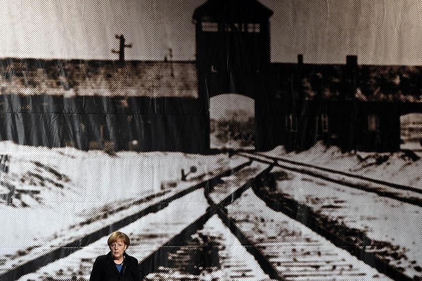 German Chancellor Angela Merkel standing in front of a historic picture of the Auschwitz concentration camp as she gives a speech during the International Auschwitz Committee’s remembrance ceremony to mark the 70th anniversary of the liberation of 