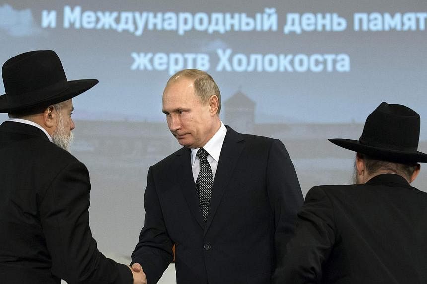 Russian President Vladimir Putin (centre) greets head of the Federation of Jewish Communities of Russia Alexander Boroda (left) and Russian Chief Rabbi Berel Lazar during a ceremony marking the 70th anniversary of the liberation of former Nazi German