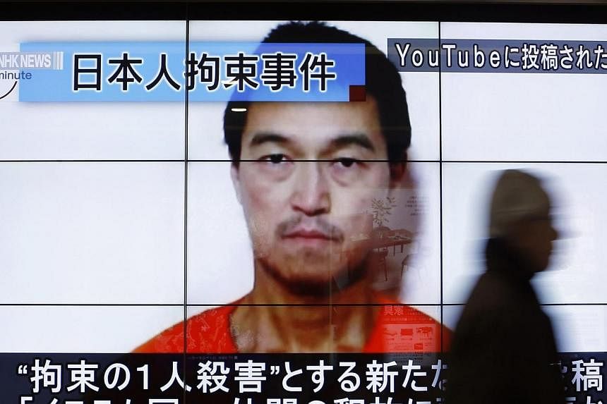 A man walking past screens displaying a news programme showing an image of Japanese journalist Kenji Goto, who is held captive by Islamic State militants, on a street in Tokyo on Jan 25, 2015. -- PHOTO: REUTERS&nbsp;