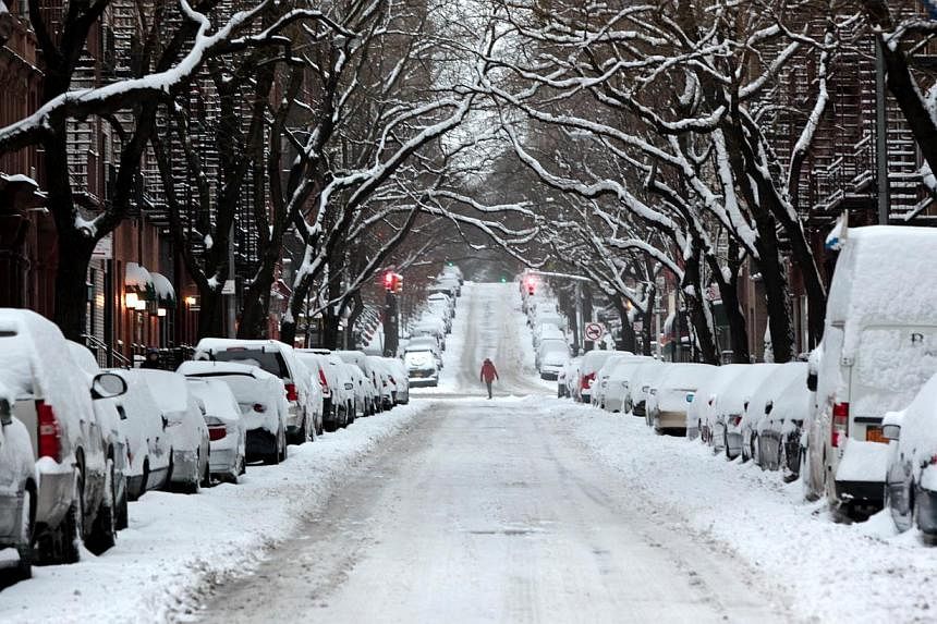 A passerby walks through an accumulation of snow on the Upper East Side of New York on Jan 27, 2015. -- PHOTO: AFP