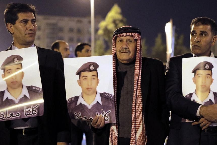 Relatives of Jordanian air force pilot Maaz al-Kassasbeh, who crashed in Syria with a F-16 last month, carry posters with his portrait and a slogan reading in Arabic, "we are all Maaz", during a protest near the Prime Minister office in Amman late on