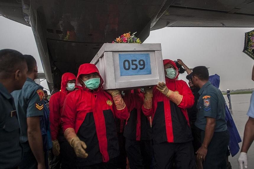 Indonesian rescuers unloading a coffin bearing a body recovered from the underwater wreckage of AirAsia flight QZ8501 from a military plane upon arrival at Surabaya on Jan 23, 2015. -- PHOTO: AFP