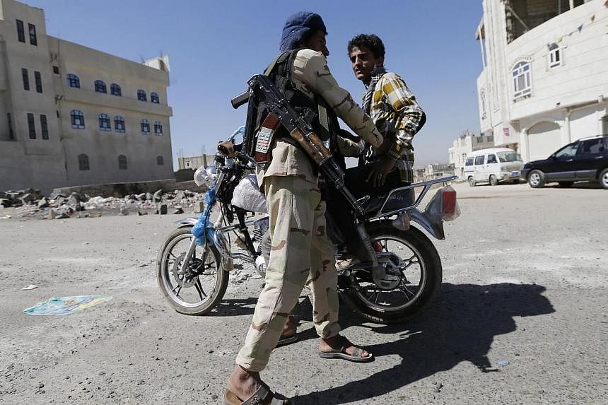 A Huthi fighter in military uniform checks a motorcyclist at a checkpoint in Sanaa Jan 27, 2015. Yemeni Shi'ite militiamen on Tuesday freed a top presidential aide whose kidnapping deepened the country’s crippling political crisis, said a person wh