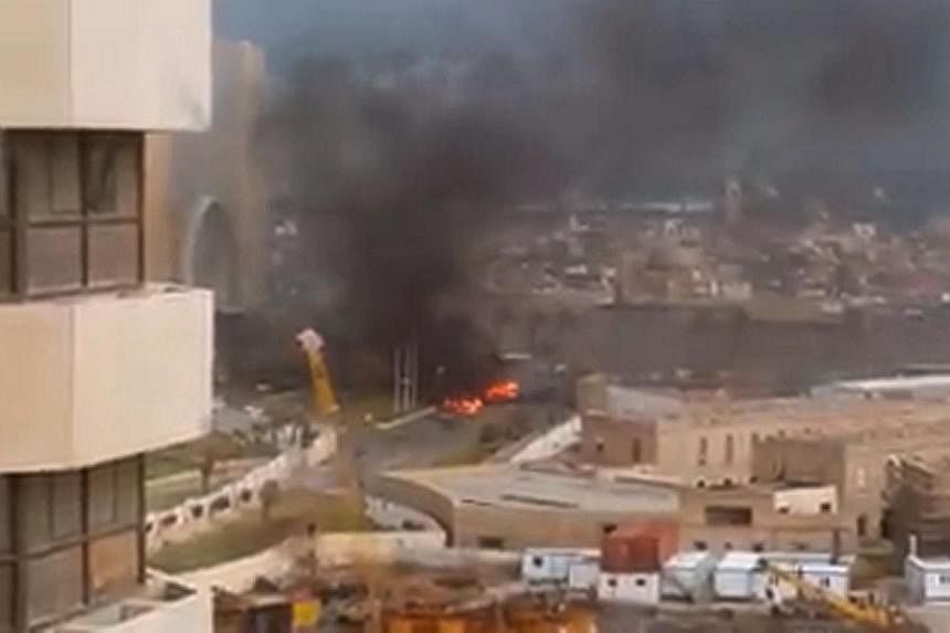 An image grab taken from an AFPTV video shows fire and smoke rising in front of the Corinthia Hotel in Tripoli on Jan 27, 2015 after gunmen stormed the luxury hotel. -- PHOTO: AFP