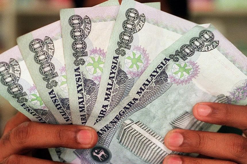 Malaysia's ringgit also dropped after Singapore unexpectedly loosened monetary policy, joining a global round of easing amid slowing economic growth and the risk of deflation. -- ST PHOTO: JEROME MING