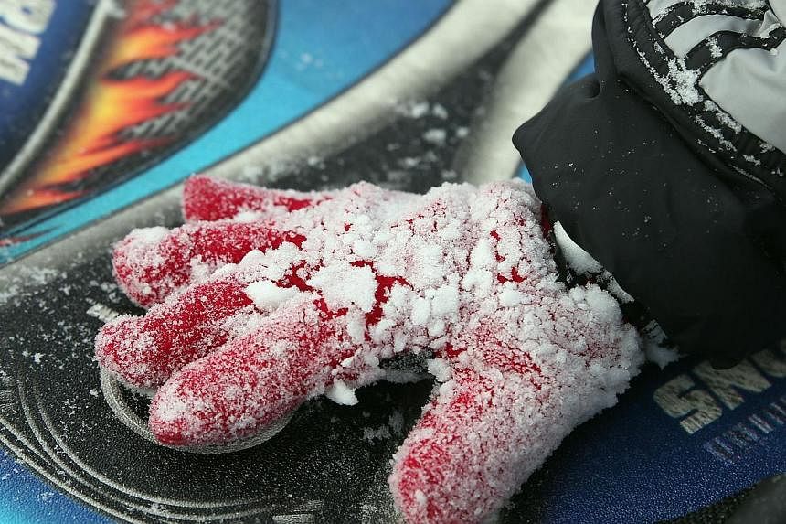 A child's glove is crusted in snow on Tuesday in Old Bethpage, New York from Winter Storm Juno.-- PHOTO: AFP&nbsp;