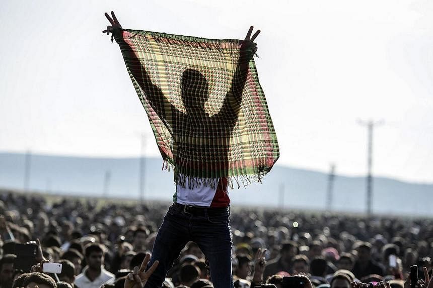 Kurdish people flash the V for victory sign during a celebration rally near the Turkish-Syrian border at Suruc on Tuesday, after ISIS group militants were expelled from the Syrian border town of Kobane, dealing a key symbolic blow to the extremists' 