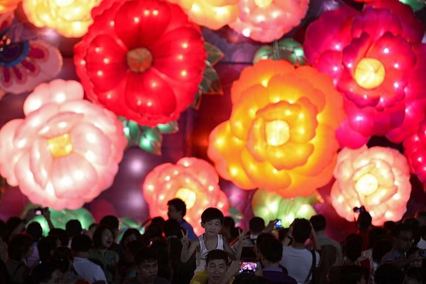 Visitors taking photos in front of the flower-shaped lanterns display at last year's River Hongbao on Feb 2, 2014. This year's celebration is set to be the biggest in its 29-year history, with aerial tightrope walkers from China's Xinjiang Autonomous