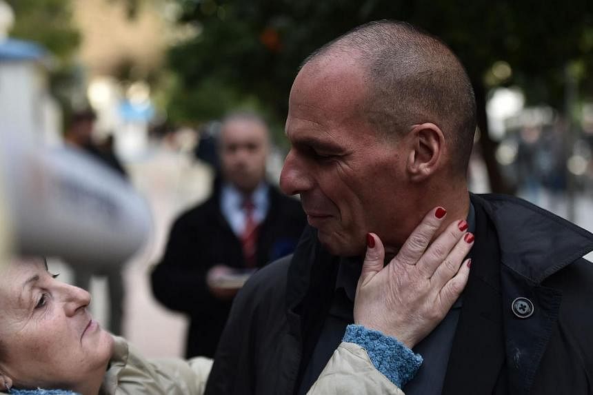 Greece's newly appointed finance minister Yanis Varoufakis (right) is greeted as he walks along a street in Athens on Jan 27, 2015. The&nbsp;53-year-old economist&nbsp;has written several books and&nbsp;worked as a consultant for computer game compan