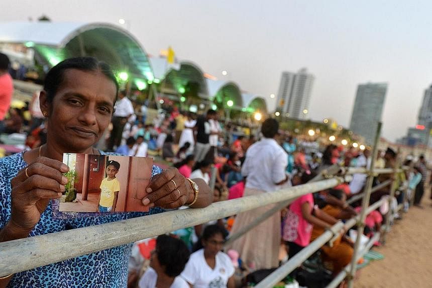 A Sri Lankan Catholic devotee holds a photograph of his close family members on his arrival the day before the celebration of the Papal Mass by Pope Francis in the capital Colombo on Jan 13, 2015. -- PHOTO: AFP