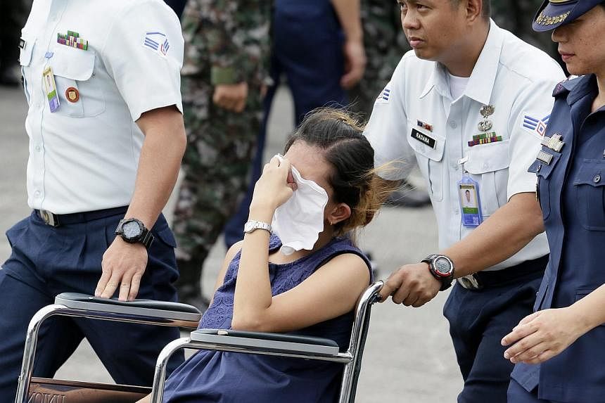 The wife of a member of elite Police Special Action Force reacting as she sits in a wheelchair while awaiting the remains of her husband at Villamor Air Base on Jan 29, 2015. -- PHOTO: EPA