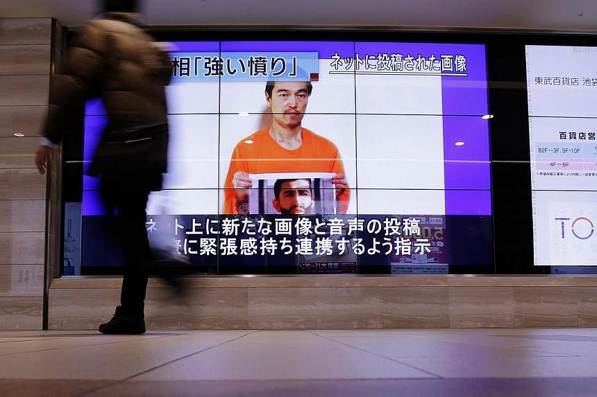 Man walks past television screens displaying a news program, about an Islamic State video showing Japanese captive Kenji Goto, on a street in Tokyo on Jan 28, 2015. -- PHOTO: REUTERS