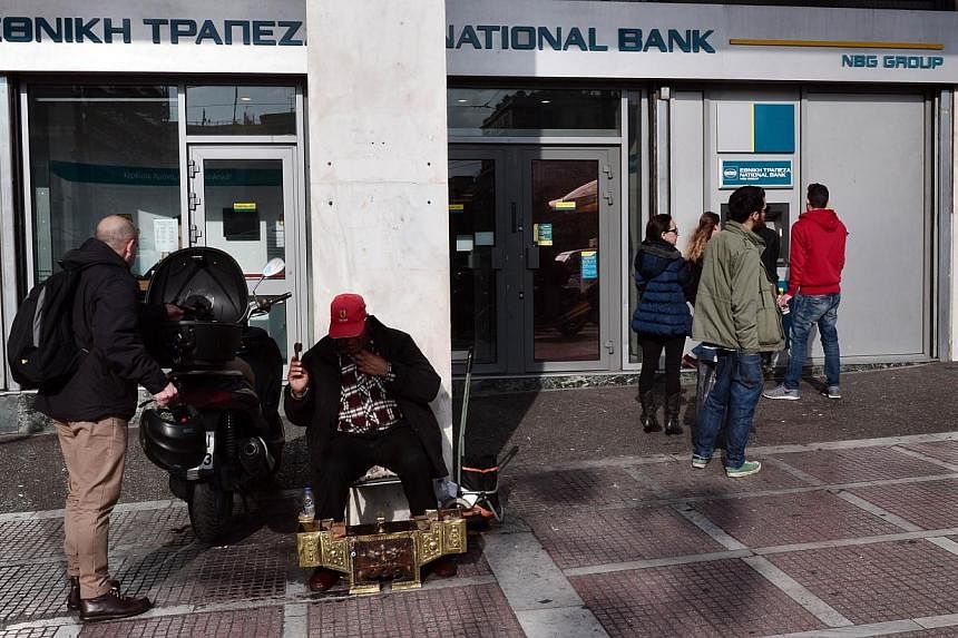 People waiting in front of a branch of the National Bank in central Athens on Jan 21, 2015. Greek banks raised more than US$11.5 billion (S$15.6 billion)&nbsp;in additional share sales in 2014, but &nbsp;lost about US$11.4 billion in market value thi