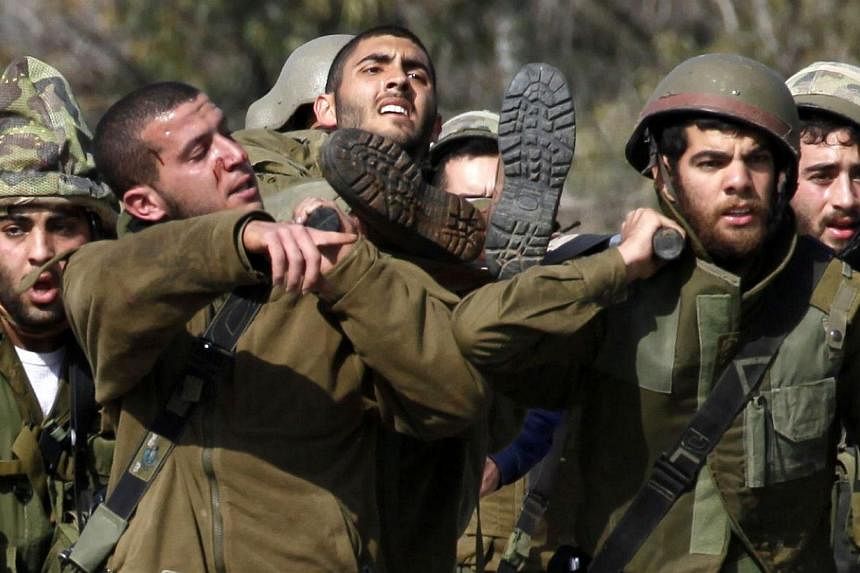 Israeli soldiers carrying their injured comrade after an anti-tank missile hit an army vehicle in an occupied area on the border with Lebanon on Jan 28, 2015. -- PHOTO: AFP