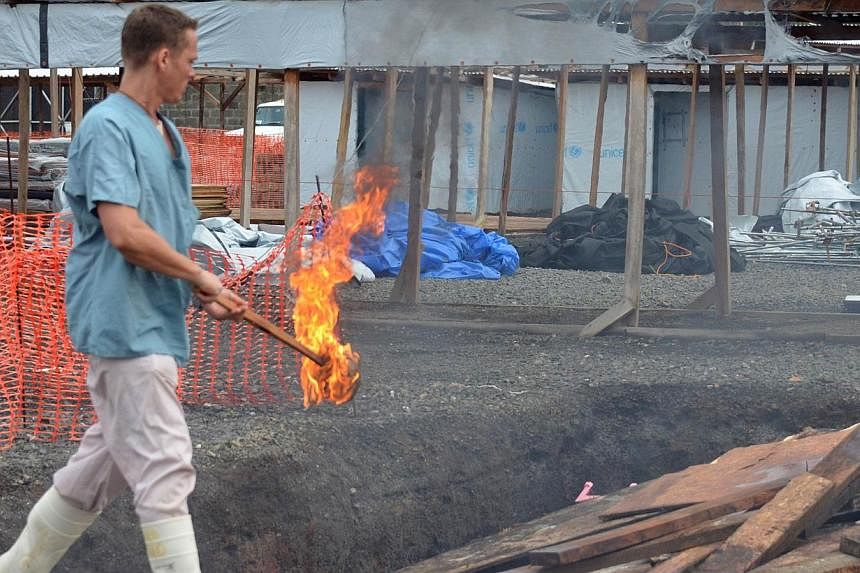 A Doctors Without Borders (Medecins Sans Frontieres, MSF) agent prepares to burn pieces of a dismantled tent on Jan 27, 2015 after the first section of the ELWA III Ebola Management Centre in Monrovia was decomissioned. Despite the epidemic decreasin