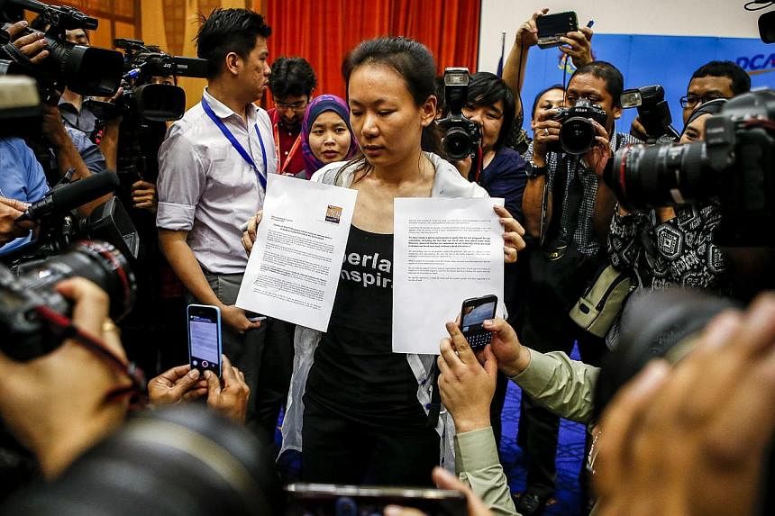 The wife of a missing Malaysia Airlines Flight MH370 passenger shows a press statement to reporters at a media conference room in Putrajaya, Malaysia, on Jan 29, 2015. -- PHOTO: EPA&nbsp;