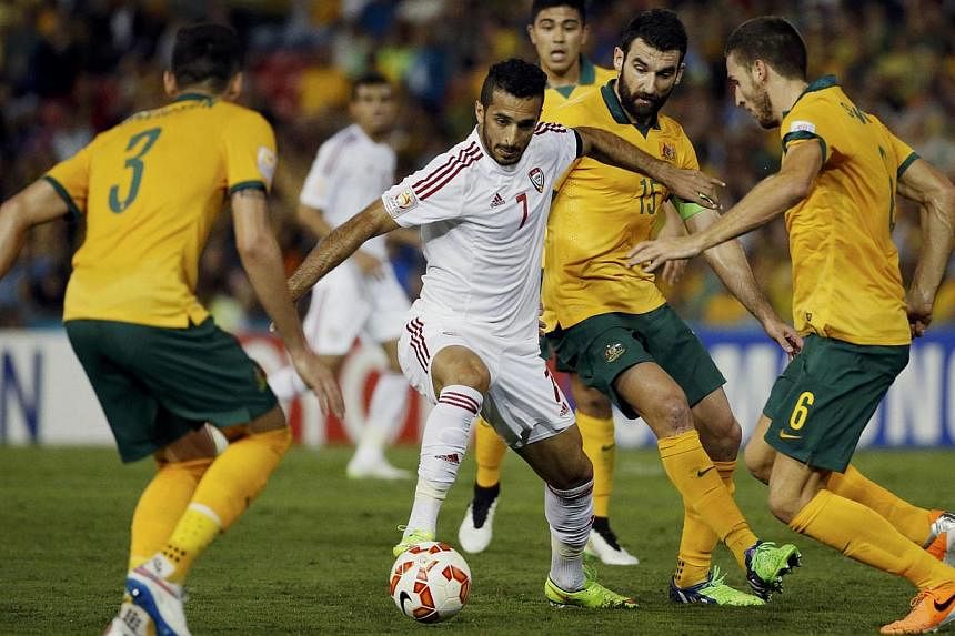 UAE's Ali Mabkhout fights for the ball with Australia's Jason Davidson (left), Mile Jedinak (2nd right) and Matthew Spiranovic (right) during their Asian Cup semi-final soccer match at the Newcastle Stadium in Newcastle on Jan 27, 2015. -- PHOTO: REU