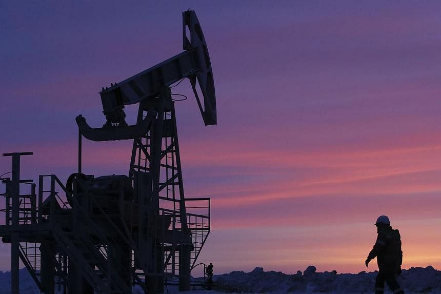A worker walks past pump jacks on an oil field in Russia on Jan 28, 2015.&nbsp;Oil tumbled to near a six-year low Wednesday as US crude stocks soared to a record high, sparking fresh fears over the growing global supply glut. -- PHOTO: REUTERS