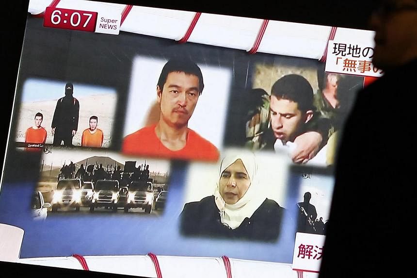 A man walking past a TV screen broadcasting a news programme about ISIS hostages Muath al-Kasaesbeh (top right), a&nbsp;Jordanian air force pilot,&nbsp;and Japanese journalist Kenji Goto (top centre), in a street in Tokyo on Jan 29, 2015. -- PHOTO: R