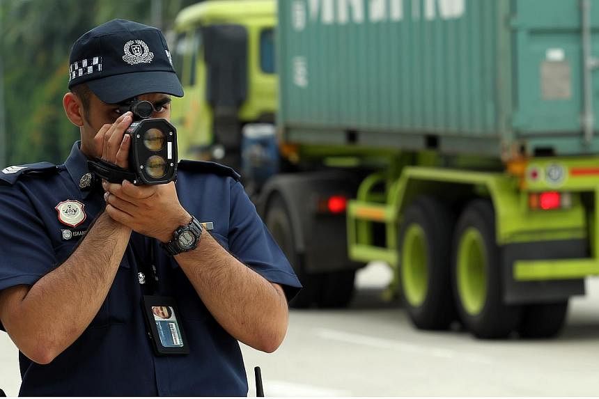 A police officer using a speed laser gun to measure the speed of vehicles from a distance. The number of drivers caught for speeding here has gone up, according to the Traffic Police. -- ST PHOTO: SEAH KWANG PENG