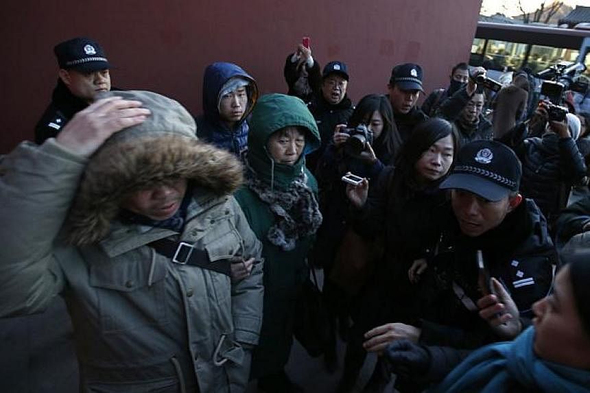 Policemen move in to stop family members (left), whose relatives were onboard the missing Malaysia Airlines Flight MH370, giving an interview to the media, in front of Yonghegong Lama Temple in Beijing on Jan 30, 2015. -- PHOTO: REUTERS