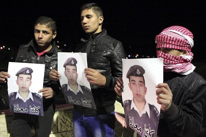 Relatives of Jordanian pilot Muath al-Kasaesbeh, who was captured by Islamic State after his plane crashed in northeastern Syria in December during a bombing mission against them, hold pictures of him at the family's headquarters in the city of Karak