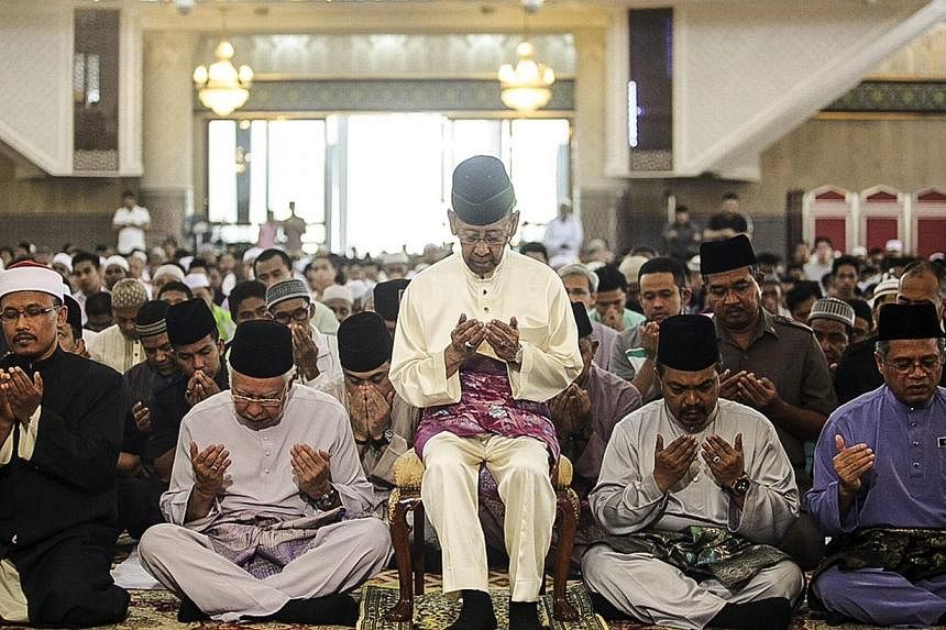 Malaysia's King Abdul Halim Mu'adzam Shah (centre) and Prime Minister Najib Razak (2nd from left), attend the special prayer to remembering the passengers and crews of MH370 Malaysian Airline missing plane at National mosque in Kuala Lumpur, Malaysia